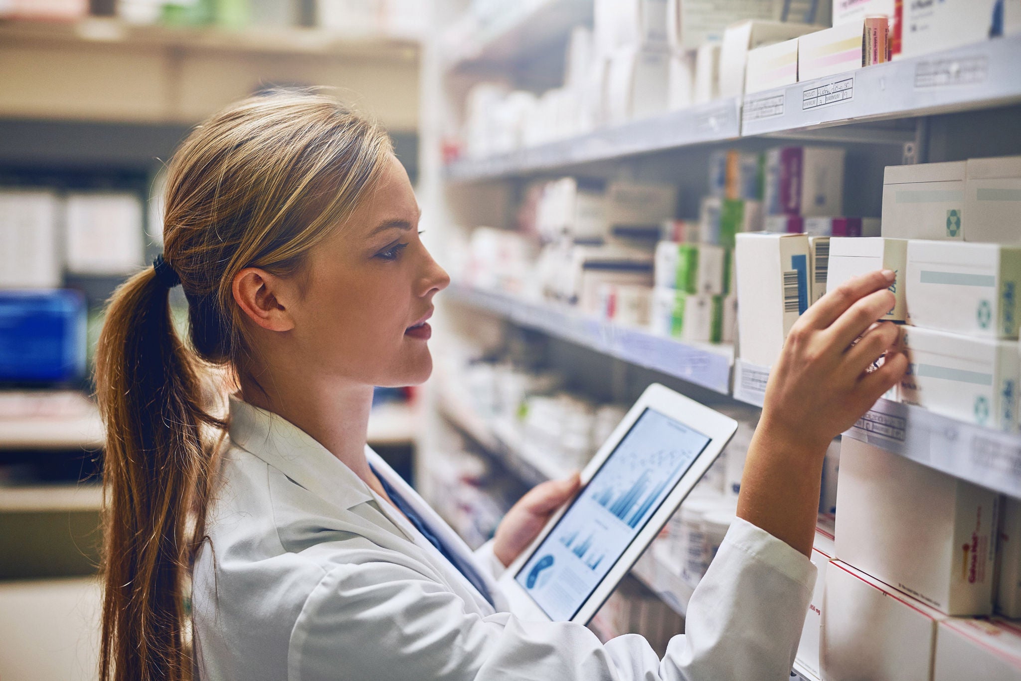 Personne en pharmacie verifiant des boites de medicaments sur tablette