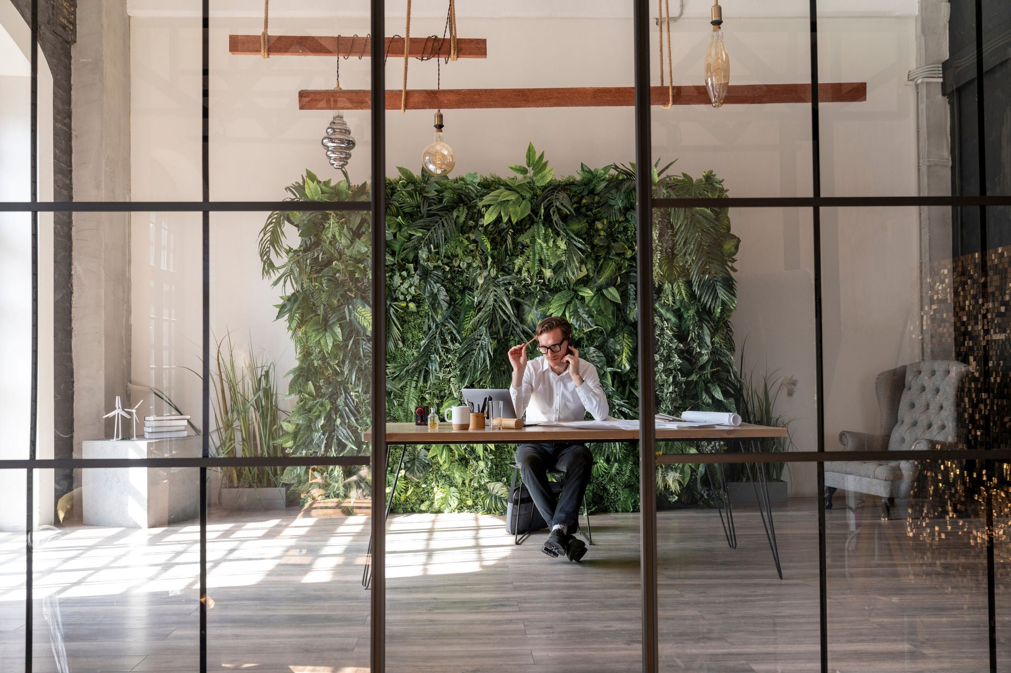 Homme travaillant à un bureau dans un bureau moderne avec un mur végétal