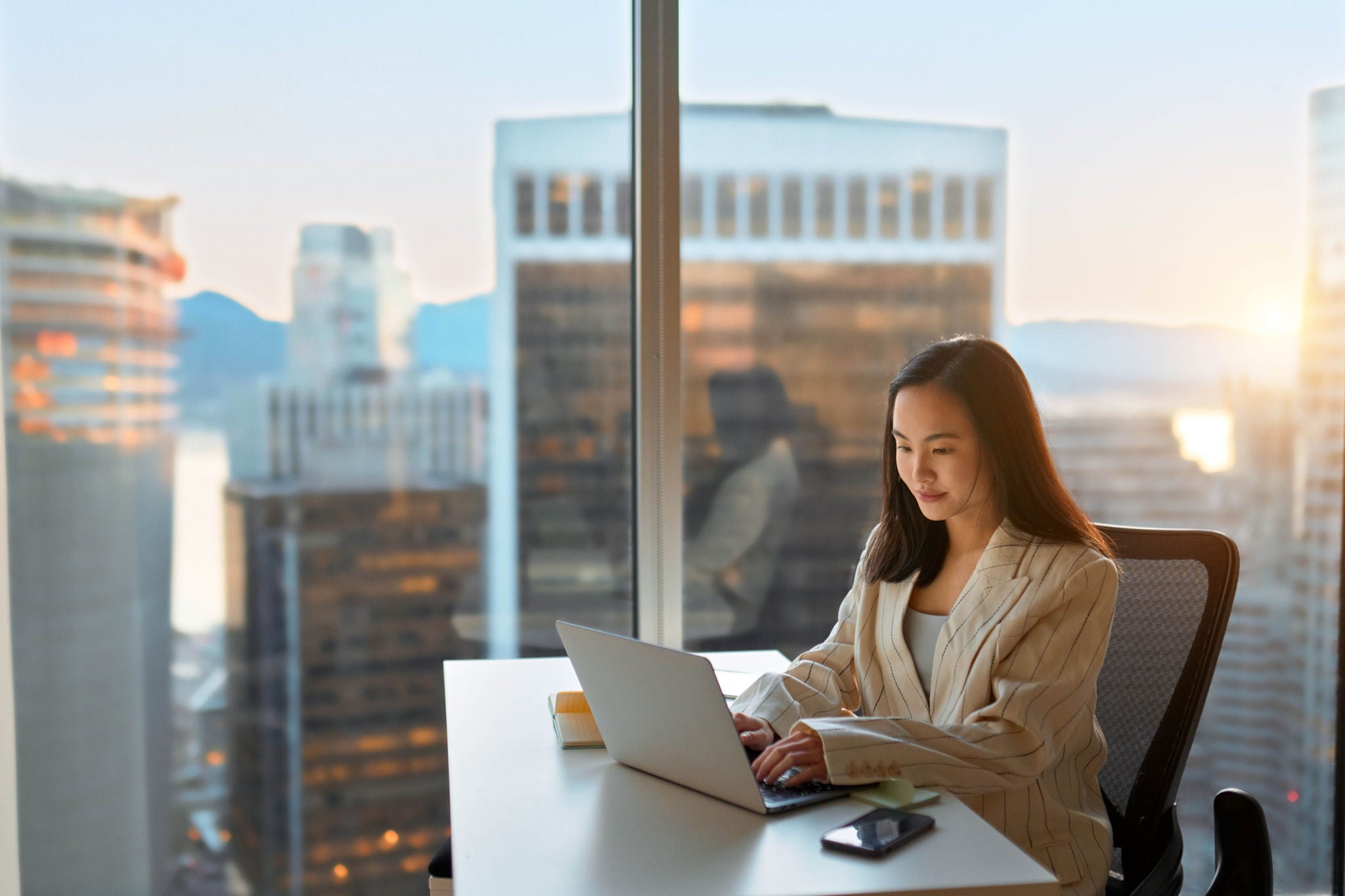 Femme travaillant sur un ordinateur dans un bureau avec vue sur la ville