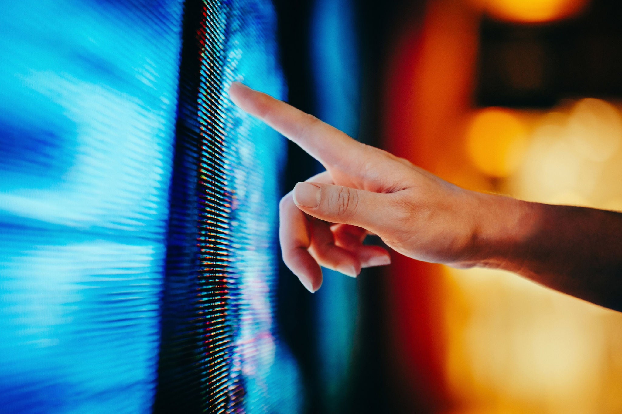 Main touchant un écran numérique affichant des motifs lumineux bleus