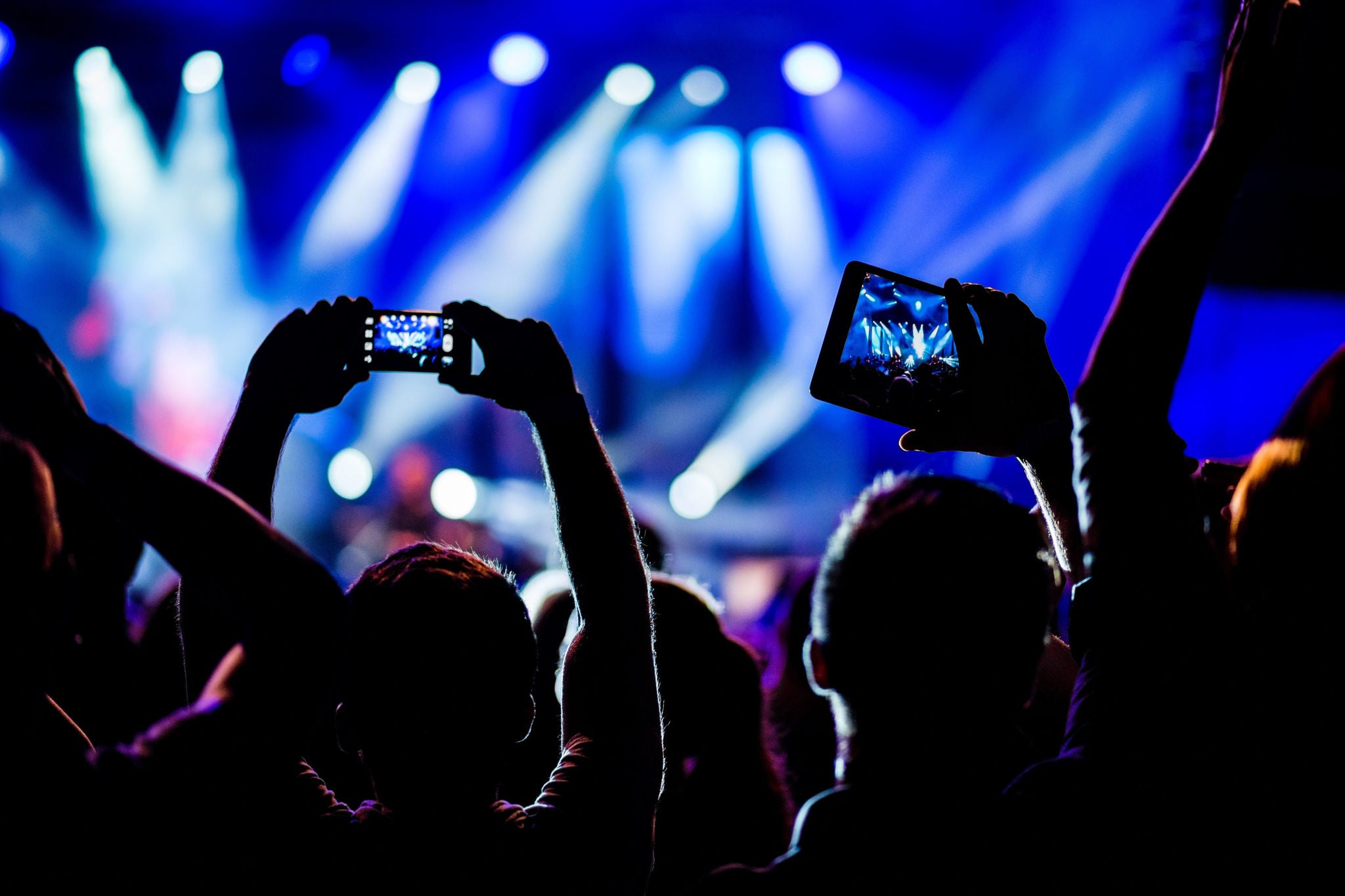 Public filmant un concert en direct avec des smartphones sous les projecteurs