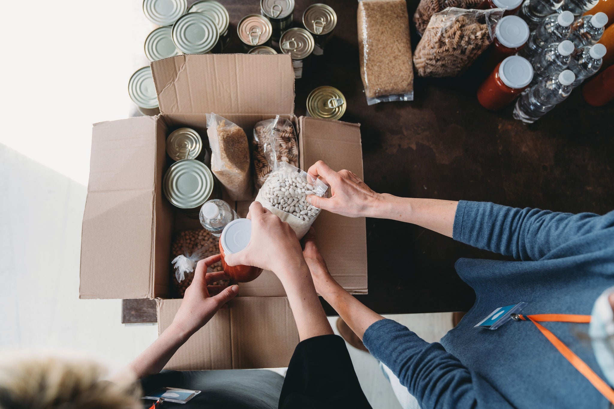 Mains emballant des denrees alimentaires dans une boite de don.