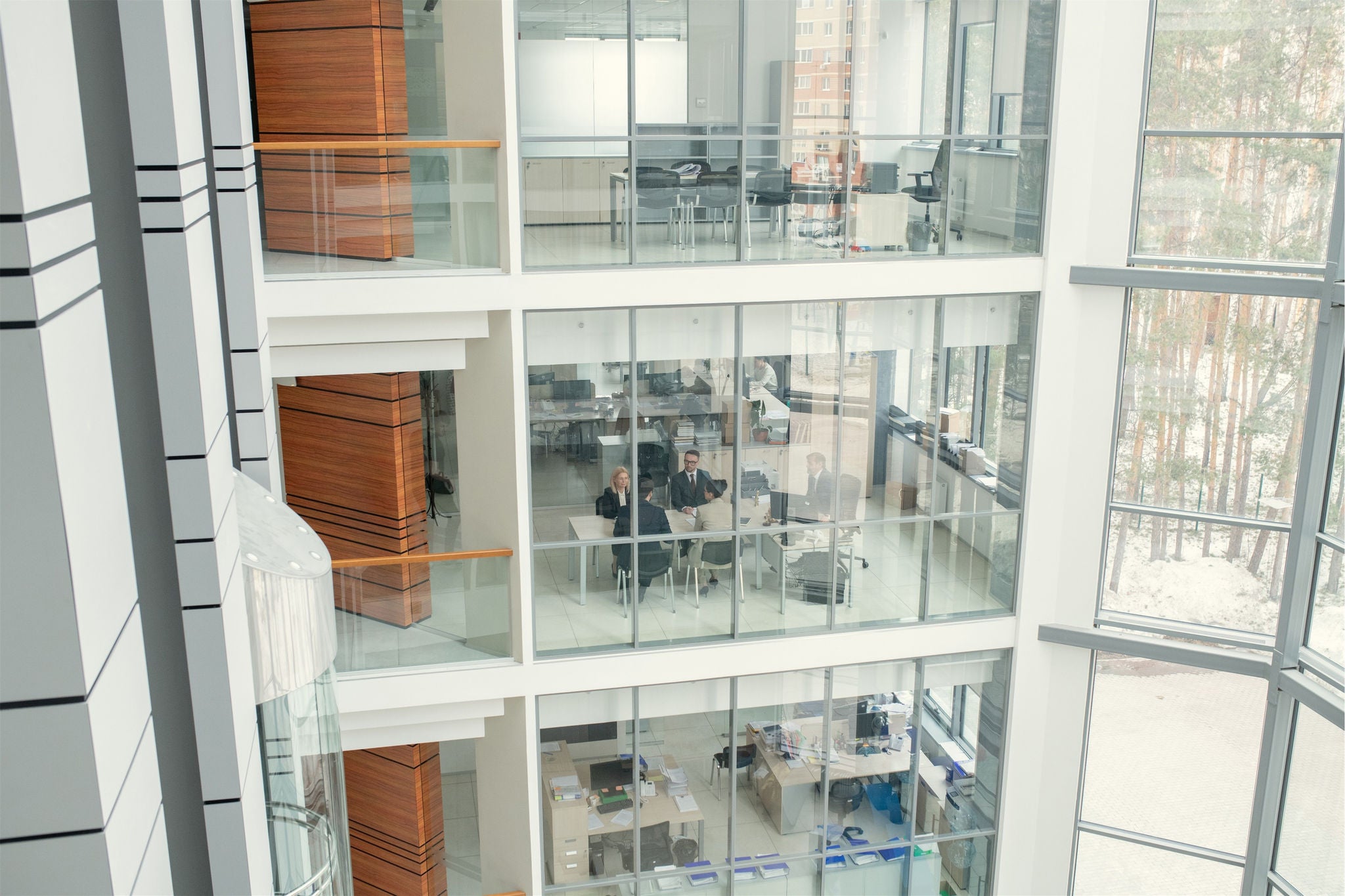 Atrium de bureaux moderne avec salles de reunion vitrees sur plusieurs etages