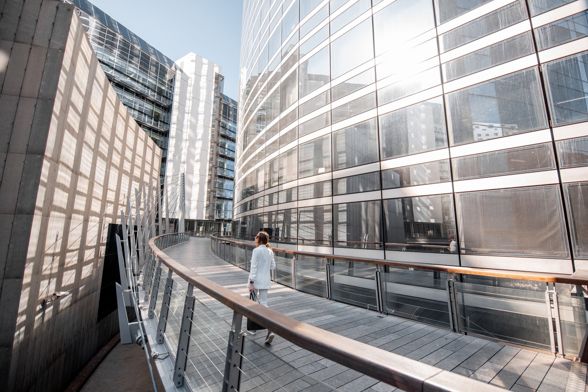 Personne sur une passerelle entre des immeubles de bureaux vitrés