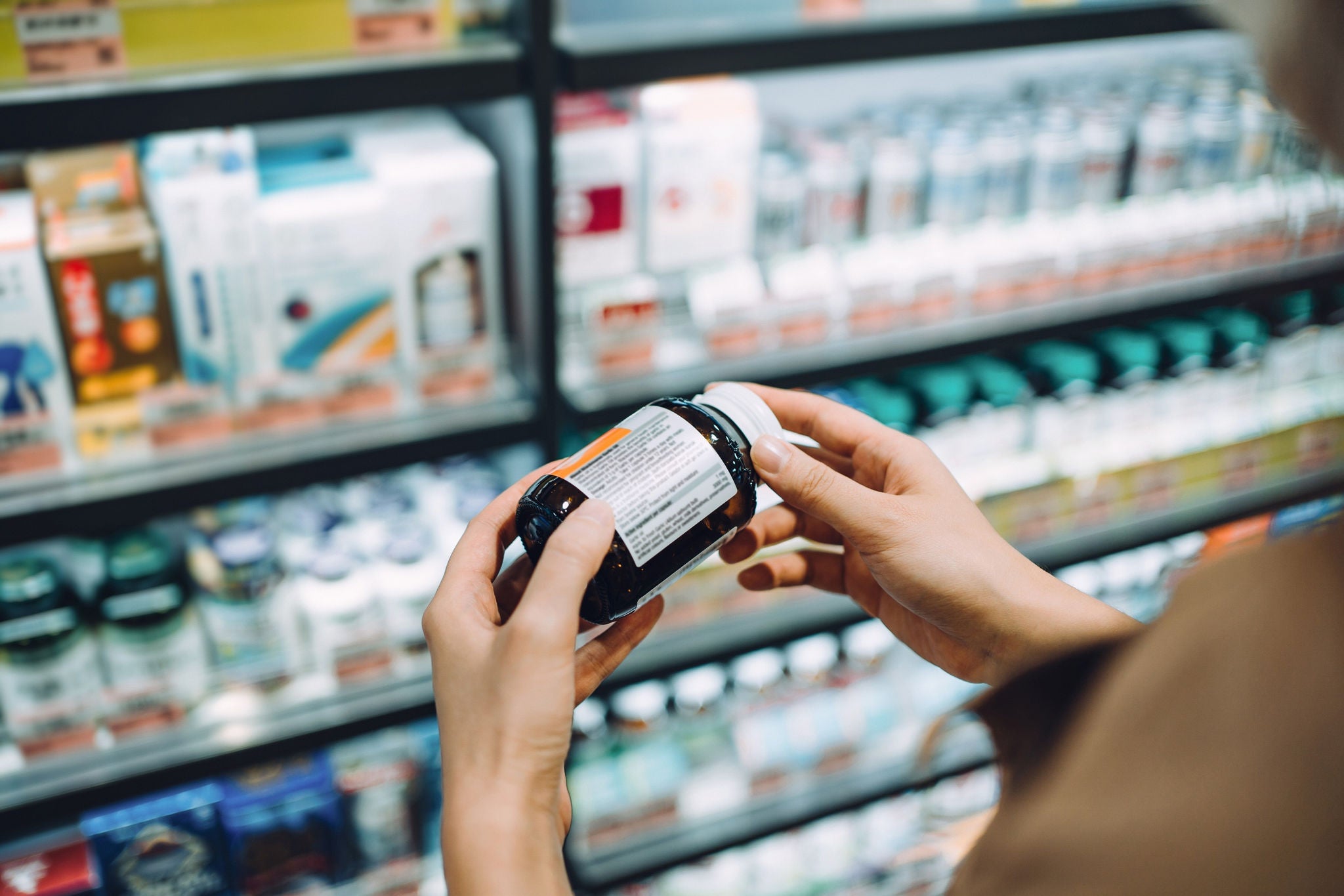 Mains tenant un flacon de médicament dans une pharmacie