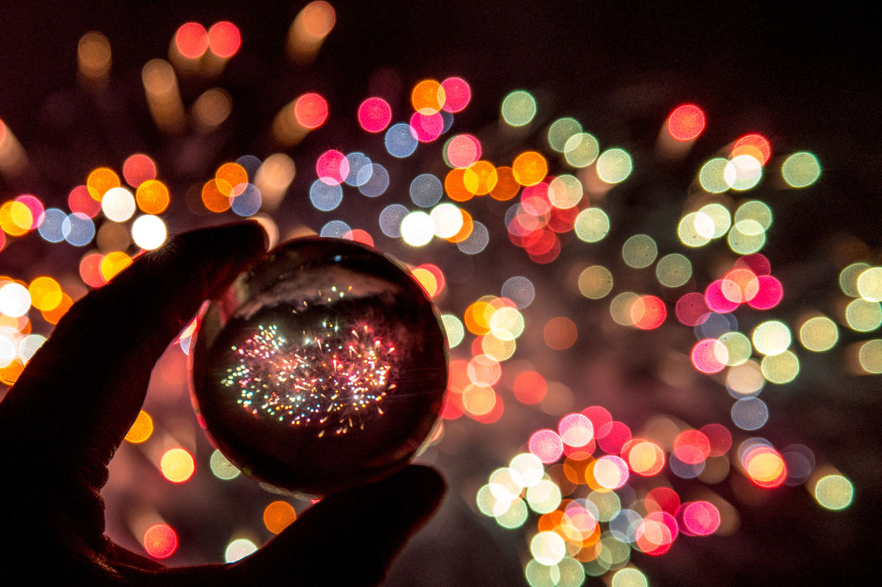 Feux dartifice refletes dans une sphere de verre et lumieres colorees